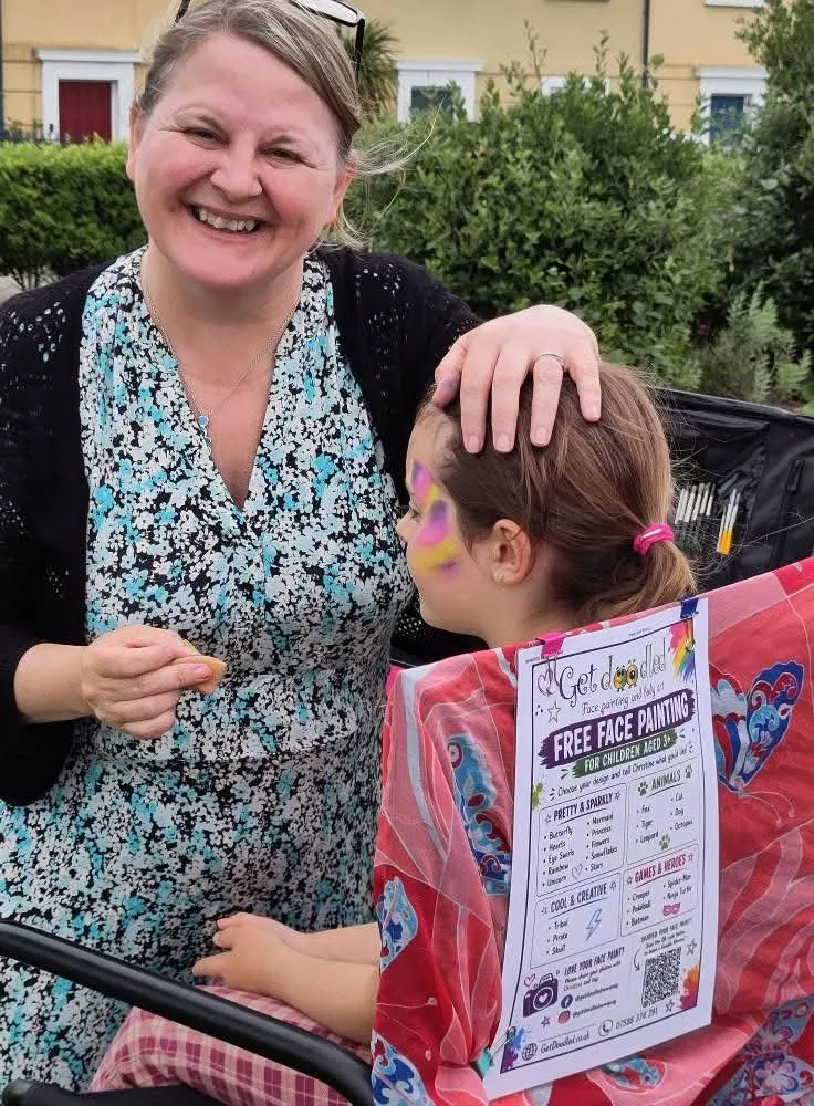 Christine at her face painting stall with a child at an event