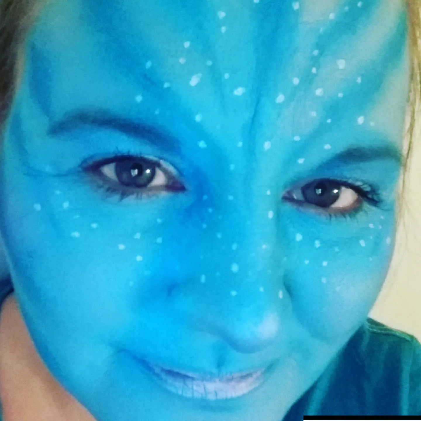 A blue Avatar-style face with white star dots