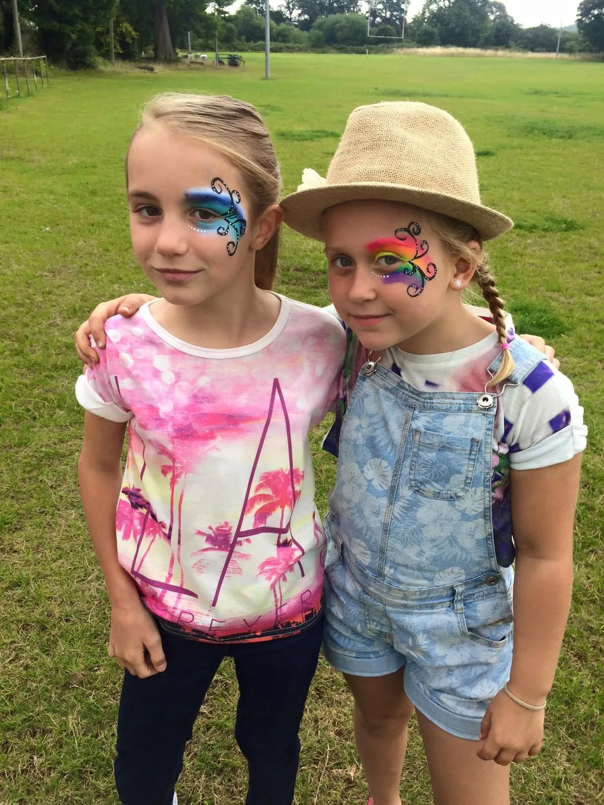 Two girls with colourful eye designs at an outdoor event