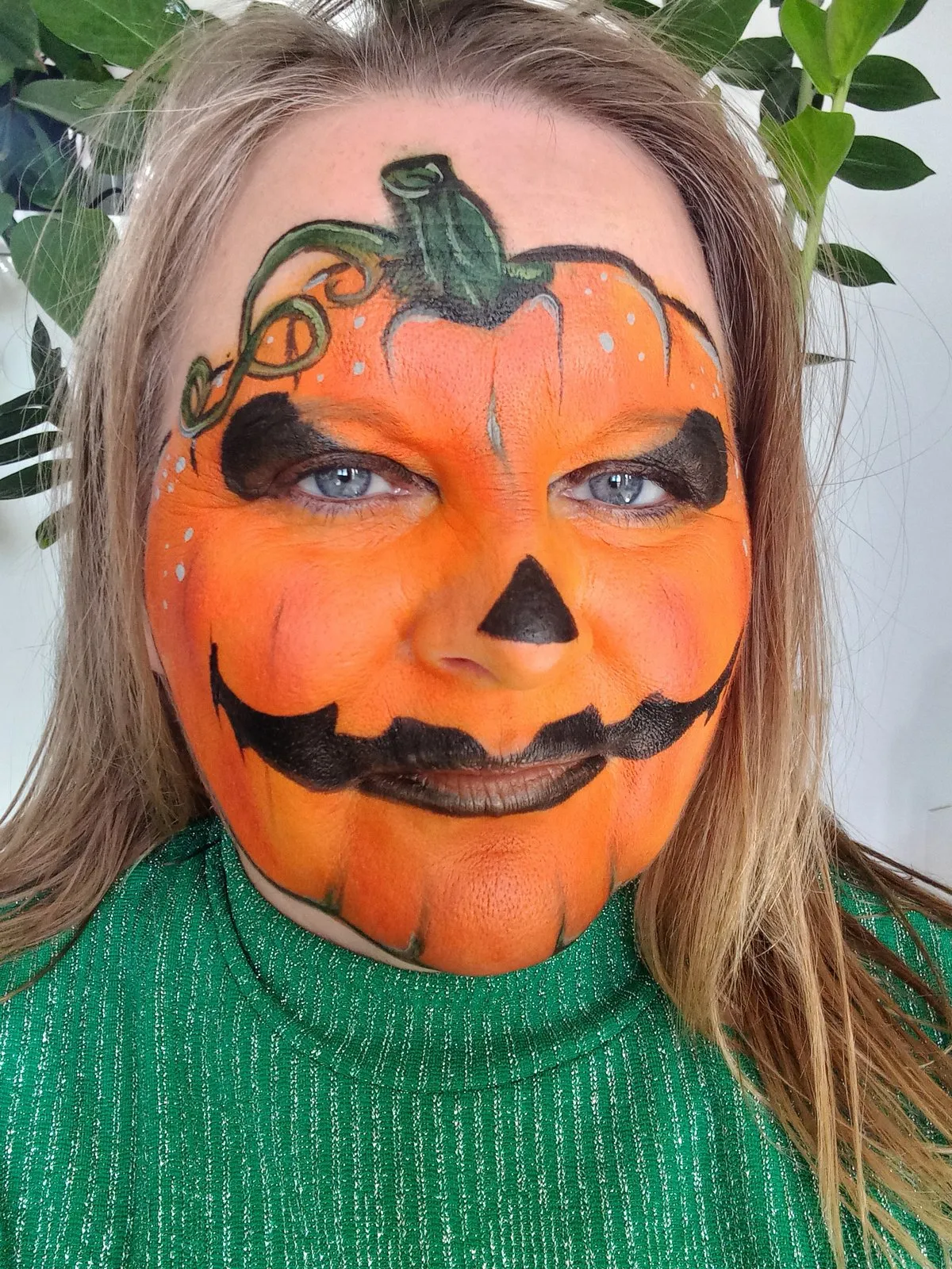 A face painted as a bright Halloween pumpkin