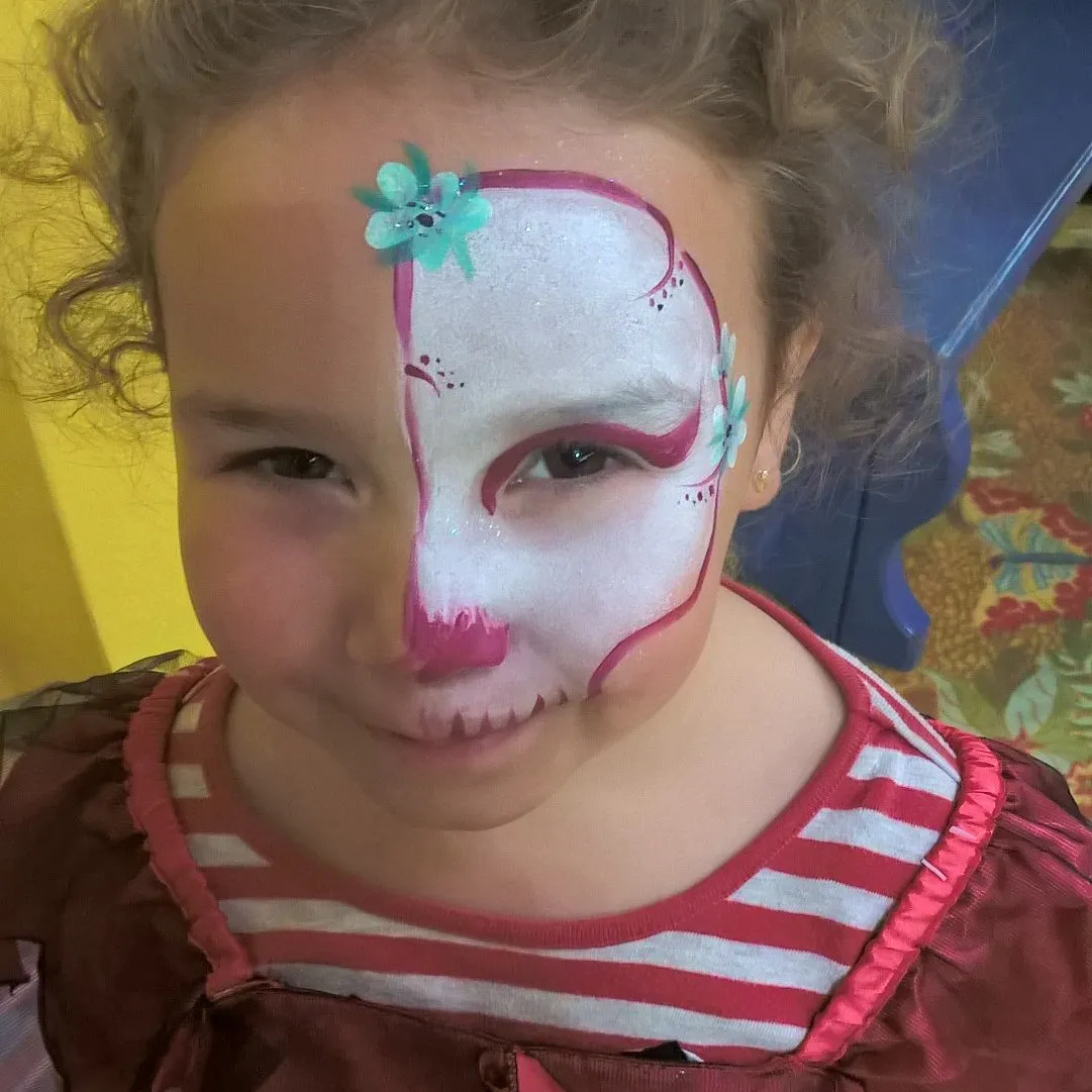 A girl with a pink sugar-skull half-face design